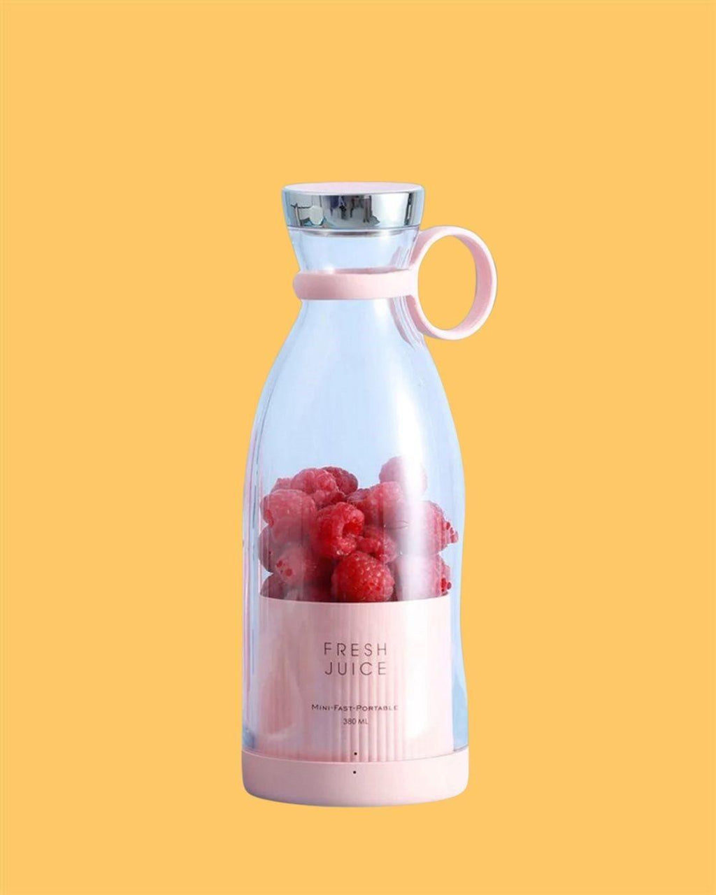 Portable electric juicer bottle with pink handle filled with raspberries on yellow background