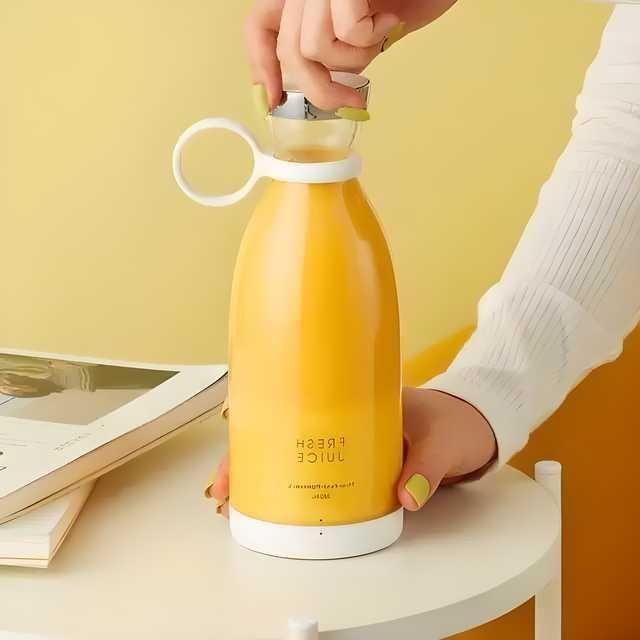 Yellow portable juicer bottle with silver lid and silicone handle placed on white table